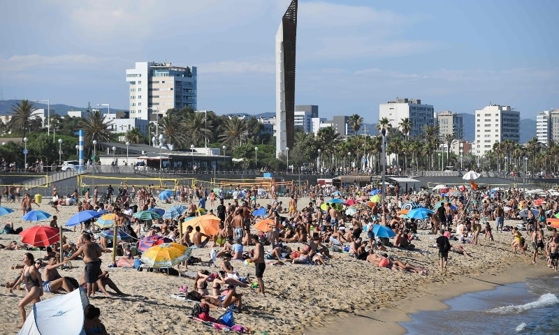 People swim and sunbathe at the Bogatell beach in Barcelona on July 19. — AFP