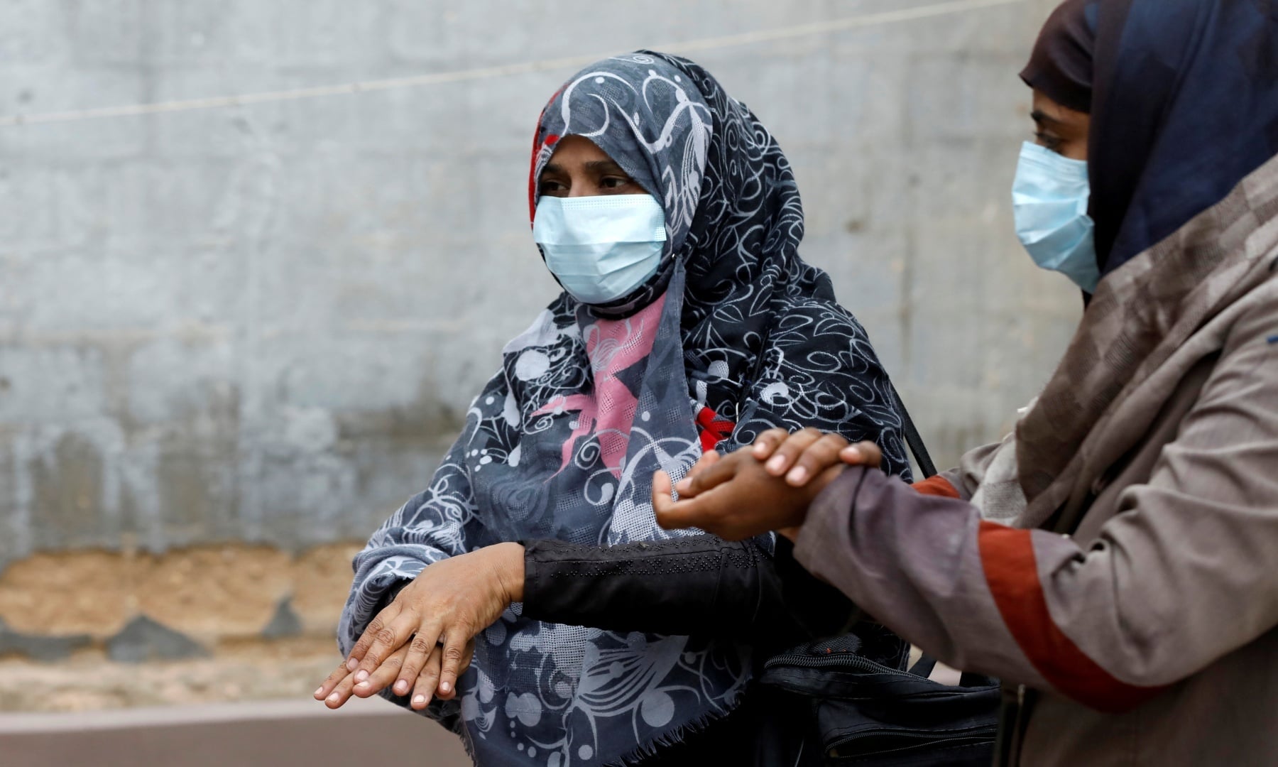 Vaccinators wear protective masks as they sanitise their hands before administering polio vaccine drops, during an anti-polio campaign in Karachi. — Reuters