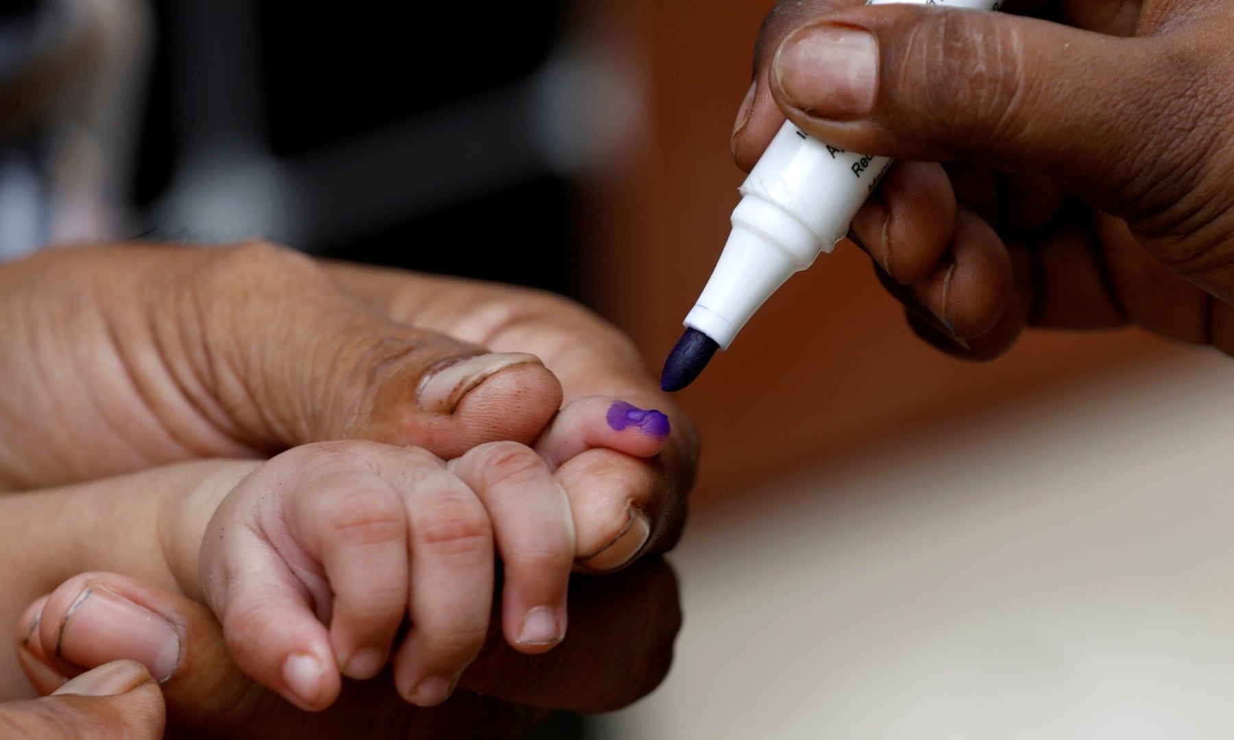 A boy gets his finger marked, after he is administered polio vaccine drops, during an anti-polio campaign, in Karachi, July 20. — Reuters