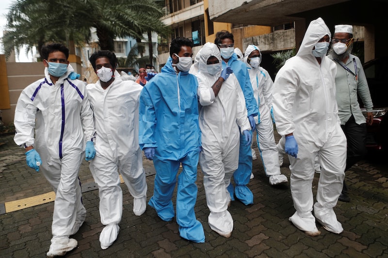 Health workers in personal protective equipment (PPE) enter a residential building complex during a check up campaign for the novel coronavirus disease in Mumbai, India, on Sunday. &mdash; Reuters