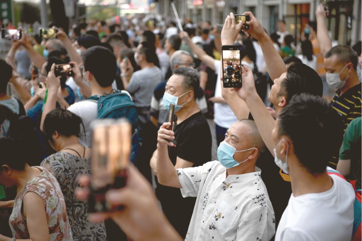 Chengdu (Sichuan province, China): People take pictures as they gather outside the US consulate on Sunday.&mdash;AFP