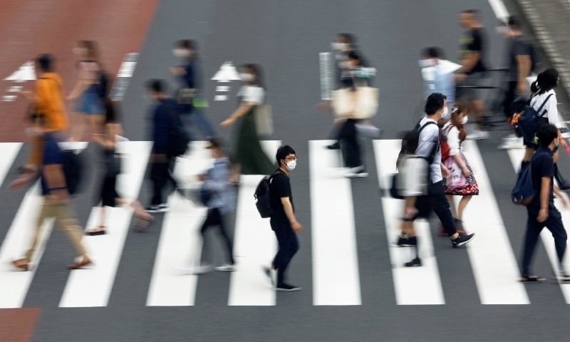 A man wearing a protective face mask crosses the street amid the Covid-19 outbreak in Tokyo on July 30. &mdash; Reuters