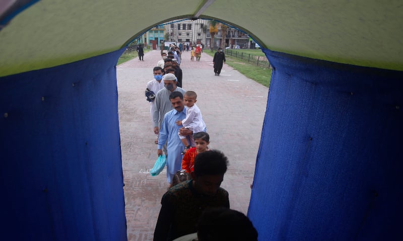 People walk through a sanitiser tunnel while entering the historical Badshahi Mosque to offer Eidul Azha prayers, in Lahore on August 1, 2020. — AP