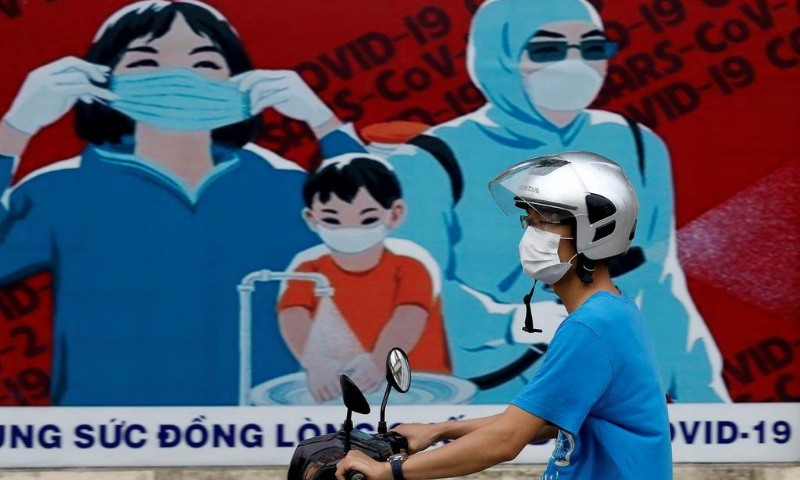 A man wears a protective mask as he drives past a banner promoting prevention against the coronavirus in Hanoi, Vietnam. — Reuters/File