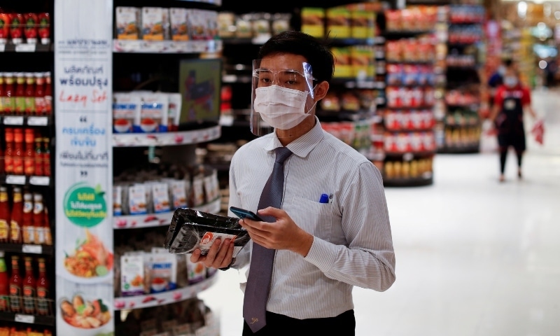 A supermarket employee wears a protective face shield and mask as he processes online orders at a shopping mall in Bangkok on May 14. &mdash; Reuters