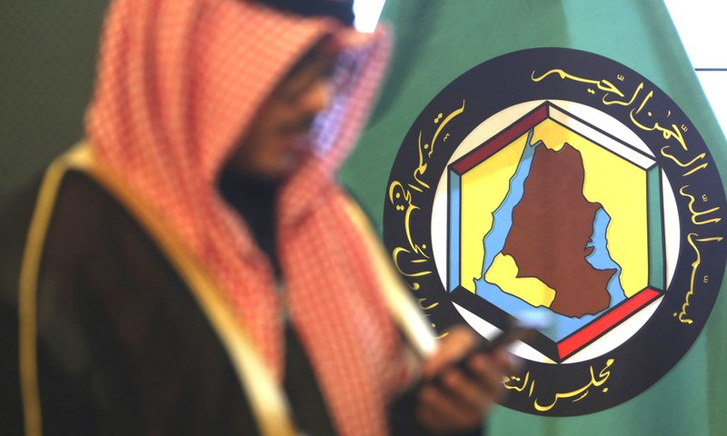 In this Dec. 5, 2017 file photo, a man looks at his mobile phone in front of the flag of the Gulf Cooperation Council, GCC, in Kuwait City. &mdash; AP