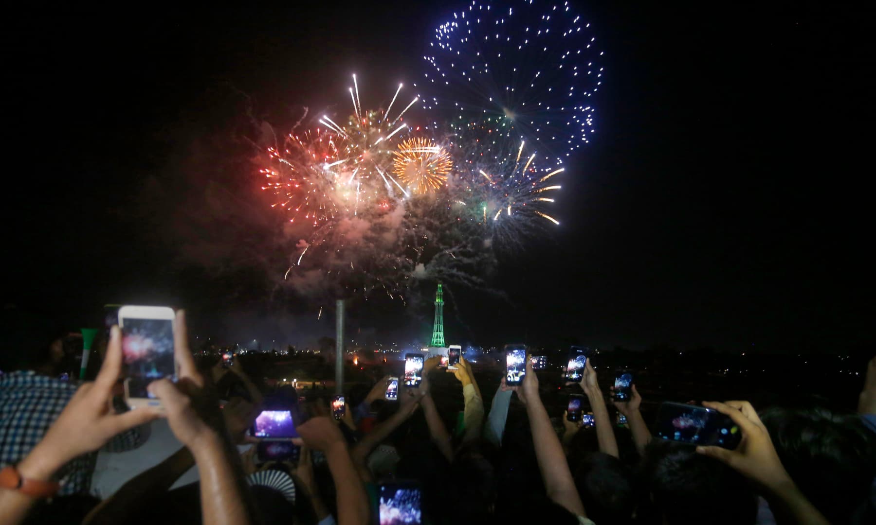 People use their mobile phones to film fireworks close to the Minar-e-Pakistan during Independence Day celebrations, in Lahore. — AP