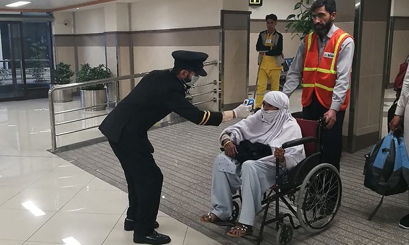An airport official checks the temperature of a passenger upon his arrival at the Bacha Khan International Airport in Peshawar on January 27, 2020. &mdash; AFP/File