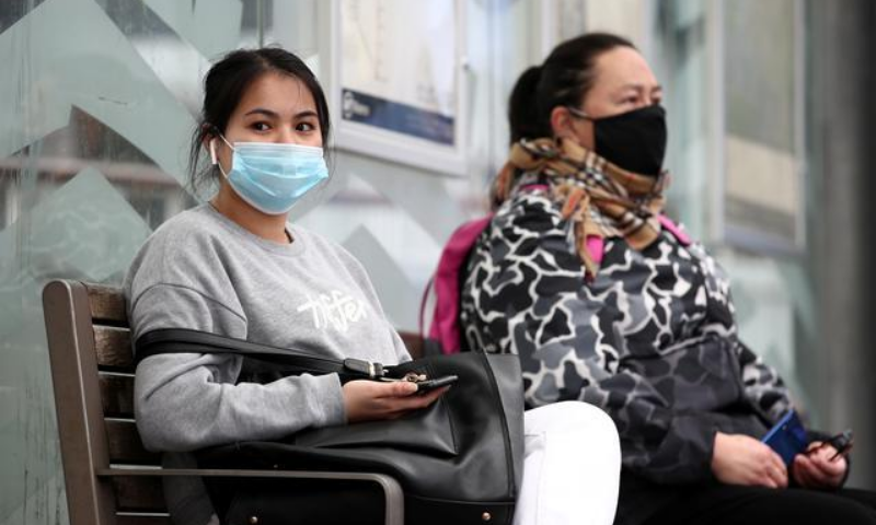People wearing a face mask wait for the bus on the first day of New Zealand's new coronavirus safety measure that mandates wearing masks on public transport. — Reuters