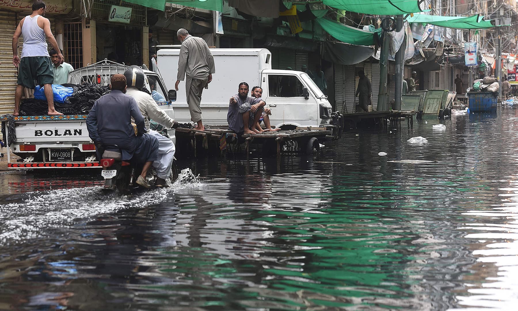 Men ride on a motorbike along a flooded street after heavy monsoon rains in Karachi on August 31. — AFP