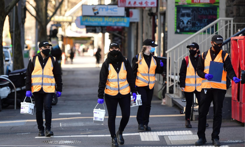 Cleaners walk down a street as the city operates under lockdown in response to an outbreak of the coronavirus in Melbourne, Australia. — Reuters