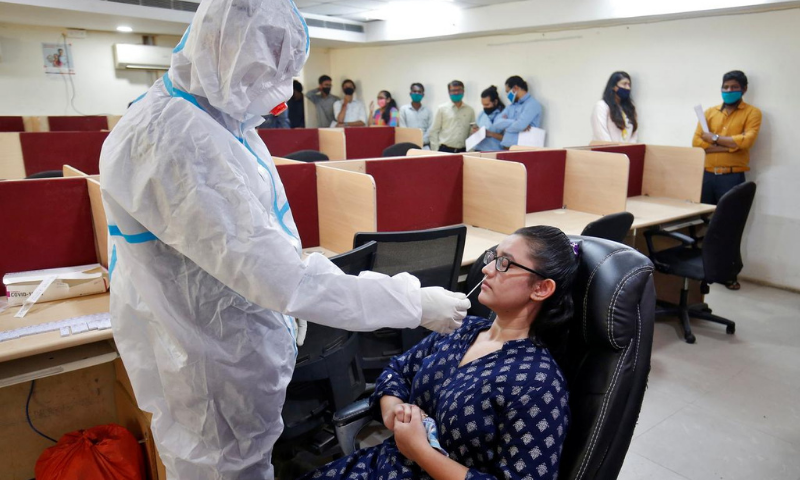 A healthcare worker wearing personal protective equipment takes a swab from a woman for a rapid antigen test inside an office, amidst the coronavirus outbreak, in Ahmedabad, India. &mdash; Reuters