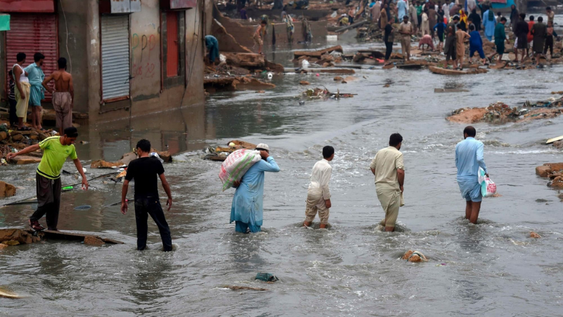 People wade through a flooded residential area after heavy monsoon rains in Karachi on August 27, 2020. — AFP