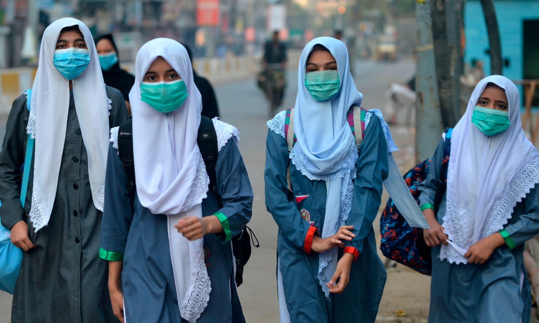 Students wearing face masks walk through a street to their school in Karachi on September 15. — AFP