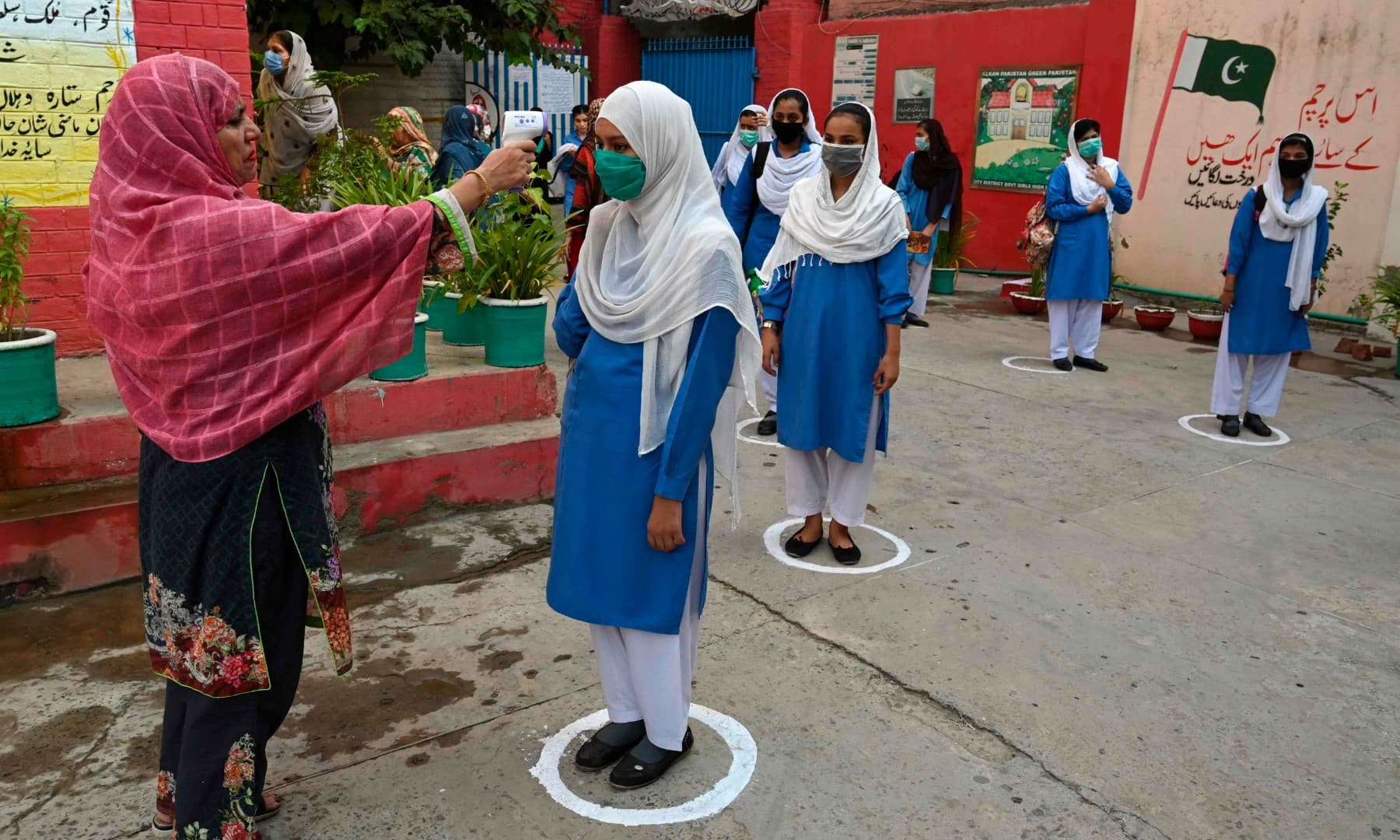 A teacher checks the body temperature of students at a government school in Lahore on September 15. — AFP