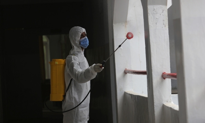 A worker sprays disinfectant in a school in Karachi on September 14. — AP