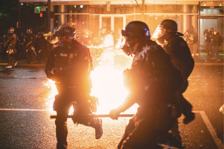 PORTLAND (Oregon): Police officers take evasive action as a molotov cocktail is thrown towards them during unrest following a grand jury’s decision in the Breonna Taylor case.—Reuters