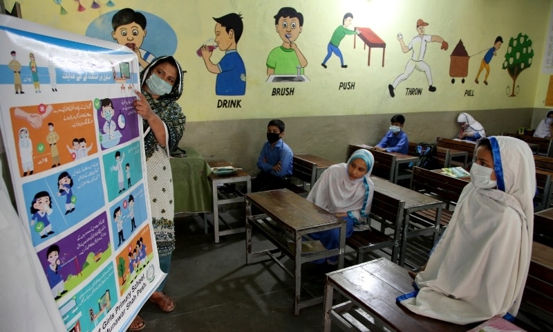 A teacher briefs about precautions of the coronavirus to students at a primary school in Peshawar on September 30. &mdash;  AP