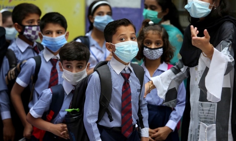 Students wearing face masks to prevent the spread of the coronavirus arrive at a primary school in Peshawar on September 30. &mdash;  AP