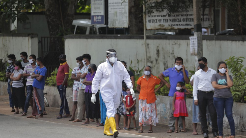 Sri Lankans wait to give swab samples to test for Covid-19 outside a hospital as a health official walks past in Minuwangoda, Sri Lanka on Tuesday. — AP