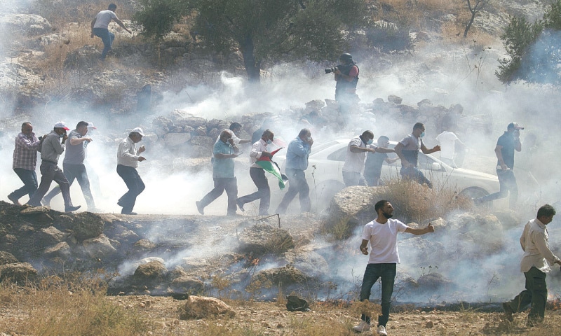 NABLUS: Palestinian protesters run amidst tear gas smoke during clashes with Israeli forces on Friday after a demonstration against the expansion of Jewish settlements.&mdash;AFP