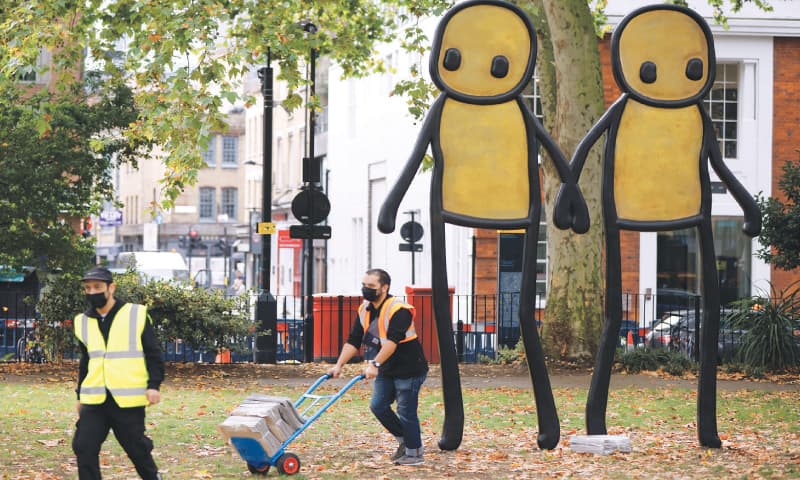 LONDON: Staff working for British street artist STIK move bundles of newspapers containing free copies of his artwork to be given away to residents during the unveiling of his bronze sculpture, Holding Hands.&mdash;Reuters