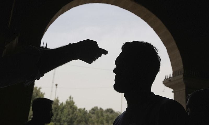 A health official checks the body temperature of a passenger at a railway station. — AP/File A health official checks the body temperature of a passenger at a railway station. — AP/File