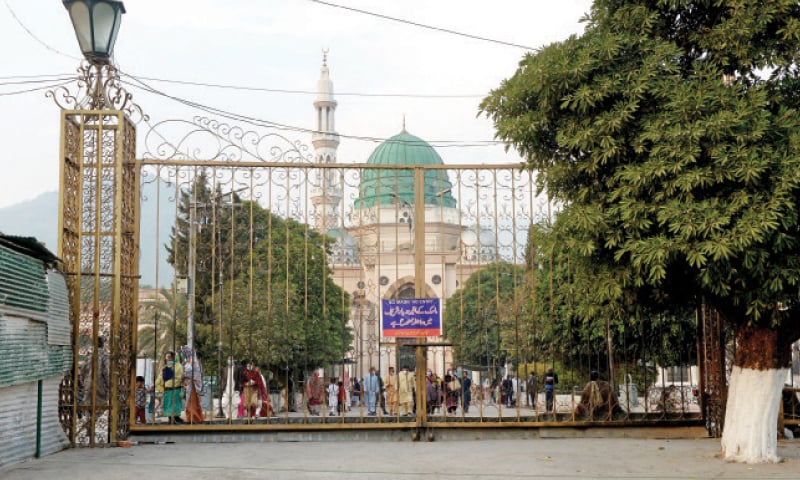 A sign displayed at the gates of Bari Imam shrine asks visitors to wear masks before entering the premises. National Command and Operation Centre on Wednesday recommended closure of shrines, cinemas and theatres in view of the rising number of Covid-19 cases. &mdash; Photo by Mohammad Asim