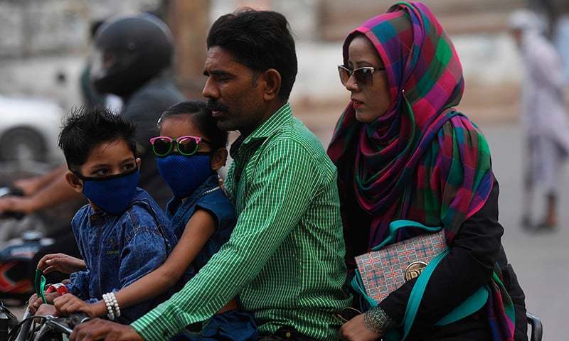 Commuters wear face masks on a street in Karachi on February 28. — AFP/File