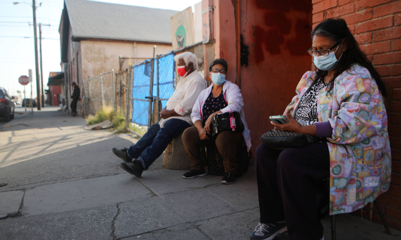 Residents sit outdoors on the sidewalk amid a surge of coronavirus cases in the city on November 18, in El Paso, Texas, US. &mdash; AFP