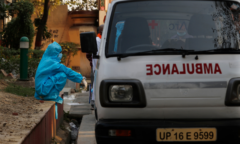 A health worker sits by an ambulance after bringing a body of a Covid-19 victim for cremation in New Delhi, India. — Reuters