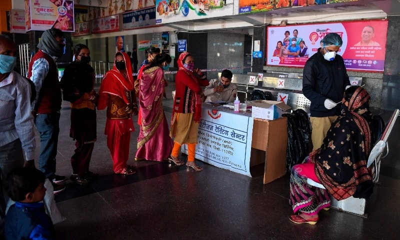 A medical worker collects a swab sample from a woman at New Delhi railway station on November 22. — AFP