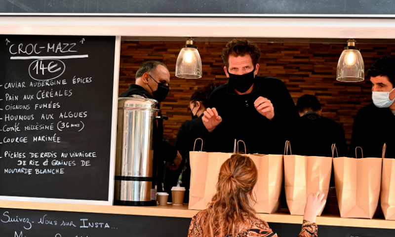 French chef Alexandre Mazzia (C) talks to a customer as his team prepares takeaway meals in a food-truck in Marseille, southern France, on November 24. — AFP