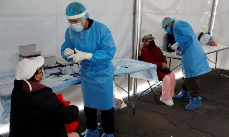 Healthcare workers wearing personal protective equipment give instructions before they take a swab sample from women for coronavirus rapid antigen testing outside the Azteca stadium in Mexico City, Mexico. &mdash; Reuters