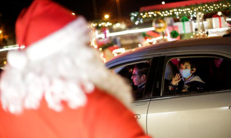 A child greets a person dressed as Santa Claus from inside a vehicle in a drive-thru Christmas village, amid the coronavirus outbreak, in Ciudad Juarez, Mexico. &mdash; Reuters