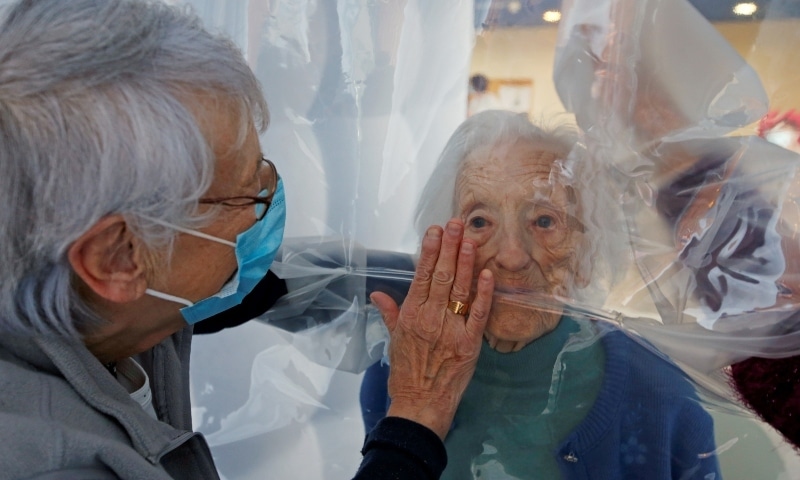 Marie-Paule and Marie-Josephe interact with their mother Colette, 97 years old, behind a removable plastic sheet inside a bubble structure which allows families to give hugs without risk of contamination or transmission of Covid-19, installed in the refectory of the Residence du Carre d'Or retirement home at Jeumont Hospital. &mdash; Reuters