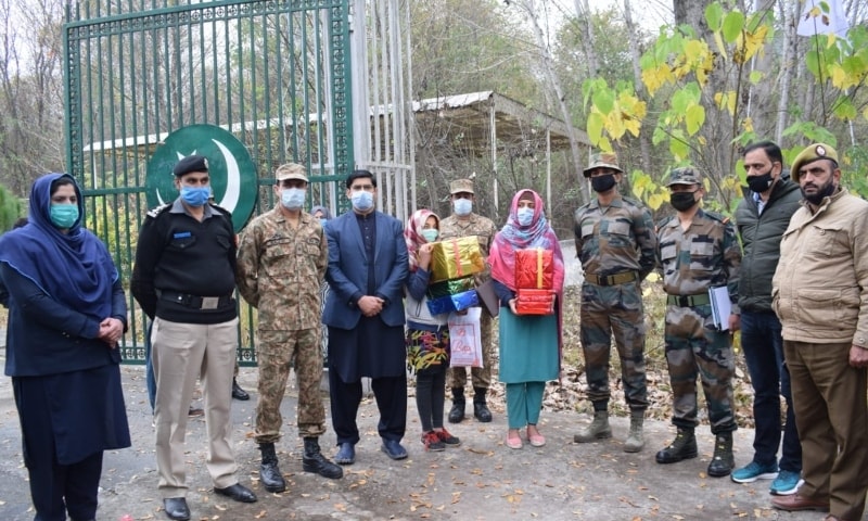 Holding gifts and sweets, Laiba and Sana stand with civilian and army officials from both sides of the divide at Tetrinote crossing point soon after their repatriation by Indian authorities on Monday.  —  Photo provided by author