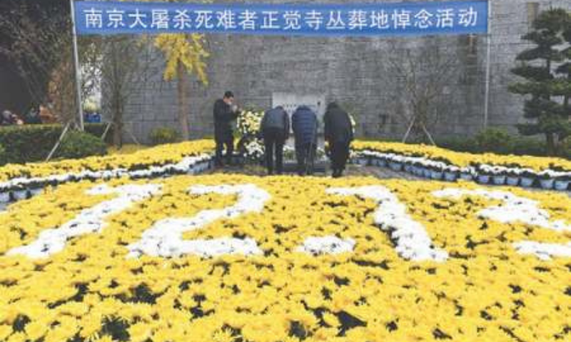 NANJING: A man takes a picture of mourners amid flowers and a banner baring the words “Nanjing Massacre Victims National Memorial” at a mass burial site during an annual commemoration of the 1937 massacre on Sunday.—AP NANJING: A man takes a picture of mourners amid flowers and a banner baring the words “Nanjing Massacre Victims National Memorial” at a mass burial site during an annual commemoration of the 1937 massacre on Sunday.—AP