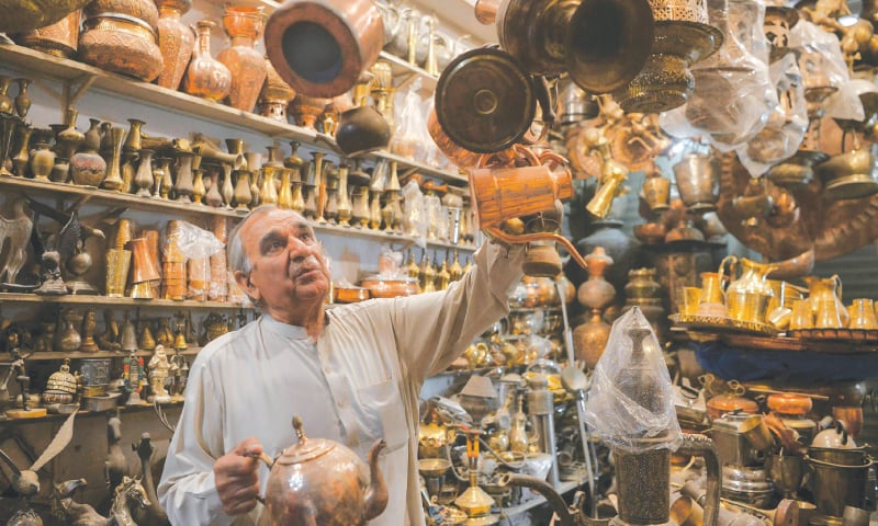 Khwaja Safar Ali arranges items in his antiques shop.—AFP Khwaja Safar Ali arranges items in his antiques shop.—AFP