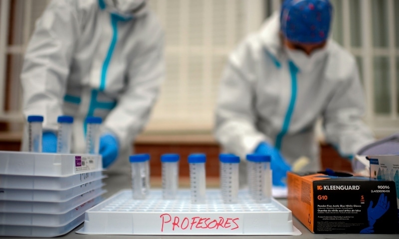 Health personnel collect saliva samples from pupils and teachers in a school in Madrid on December 17. — AFP Health personnel collect saliva samples from pupils and teachers in a school in Madrid on December 17. — AFP