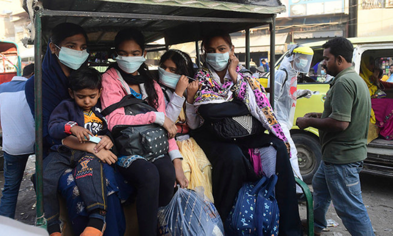 A family wearing facemasks as a preventive measure against the Covid-19 coronavirus sit in a three wheeler vehicle along a street, in Karachi on December 14. — AFP/File