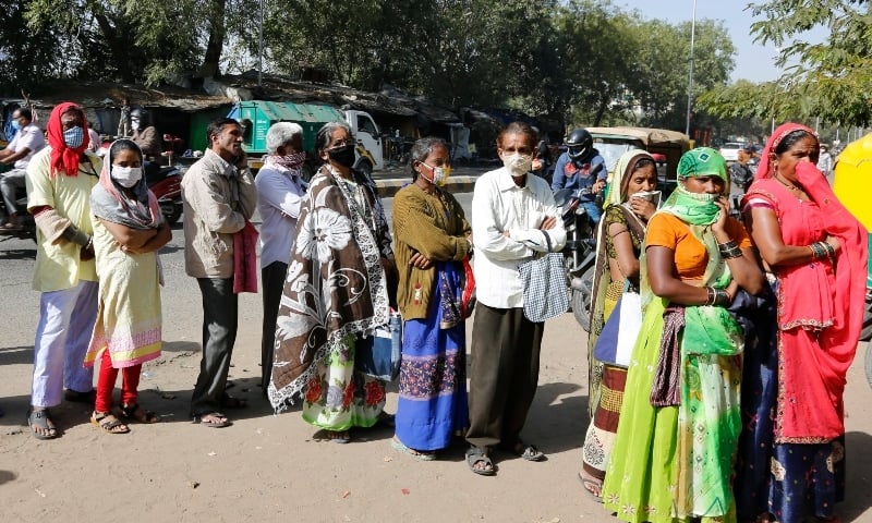 Indians wearing face masks as a precaution against the coronavirus line up outside a bank in Ahmedabad on Dec 28. — AP