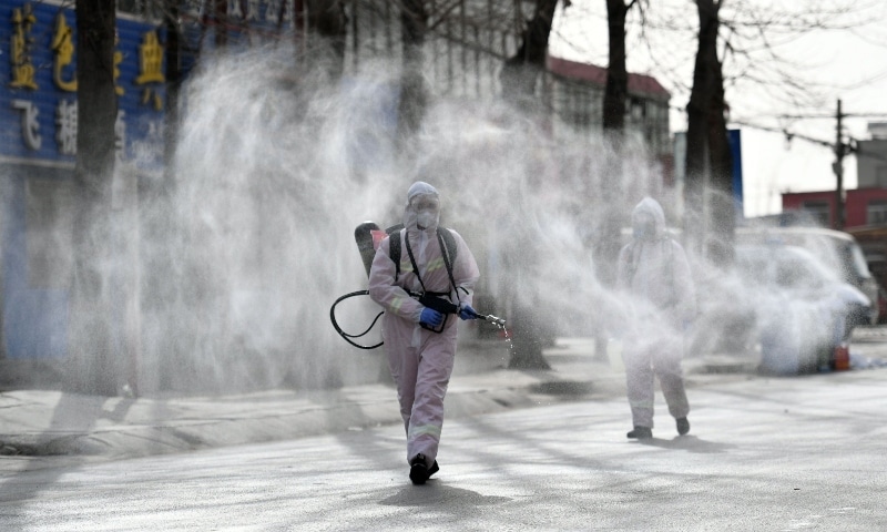This photo taken on January 15, 2021 shows people in protective suits spraying disinfectant on a street at Gaocheng district. &mdash; AFP