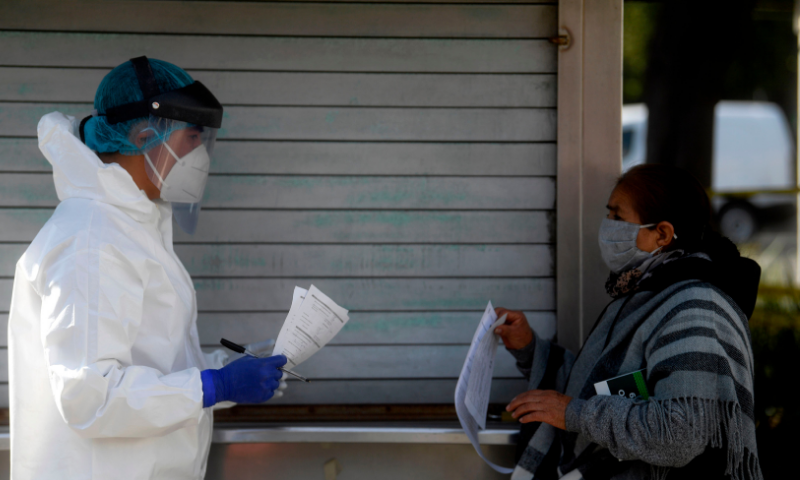 A woman queues to receive a SARS-CoV-2 rapid antigen test at a temporary tent, in Mexico City on Saturday. — AFP