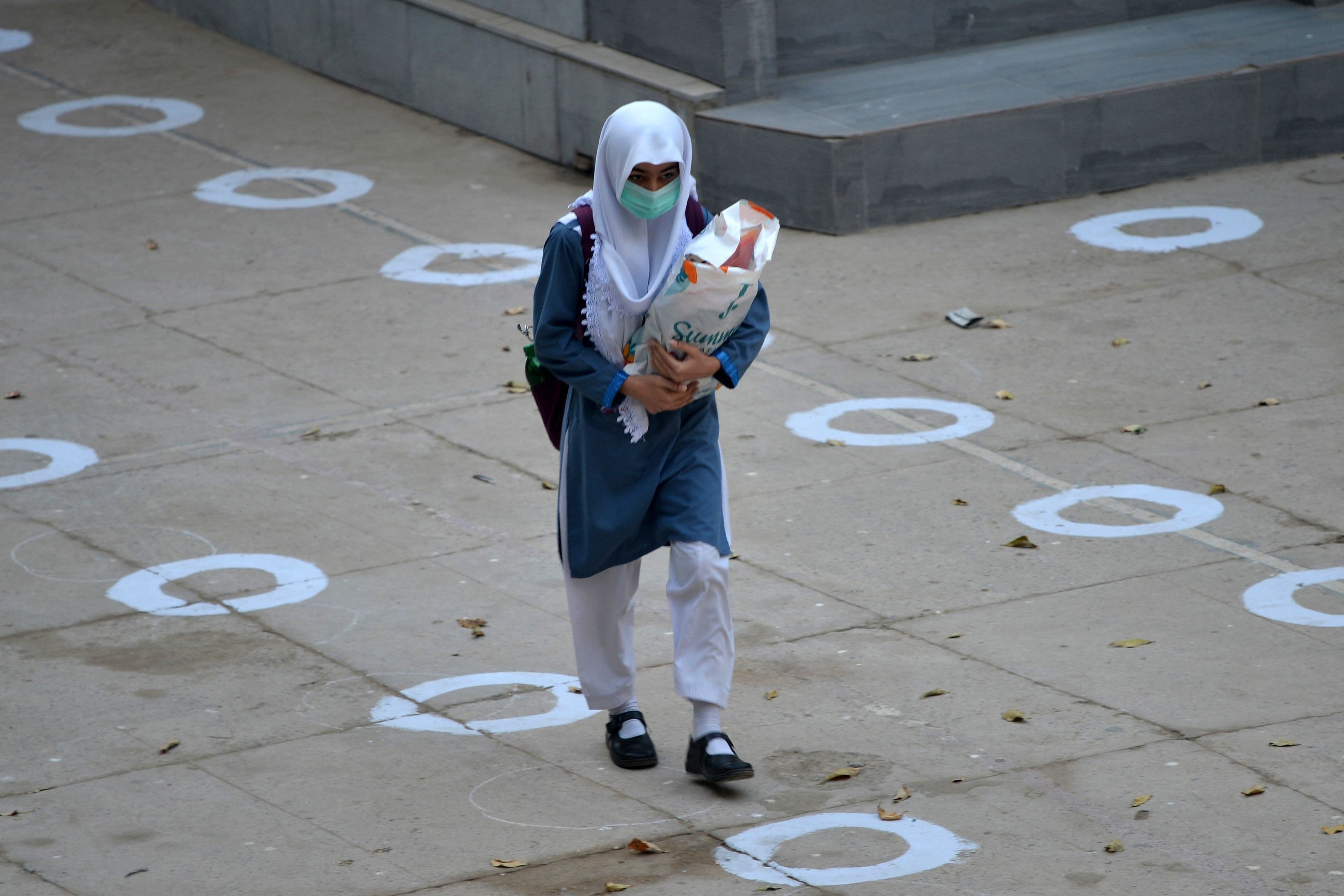 A student wearing a facemask arrives at the school in Karachi on January 18. — AFP