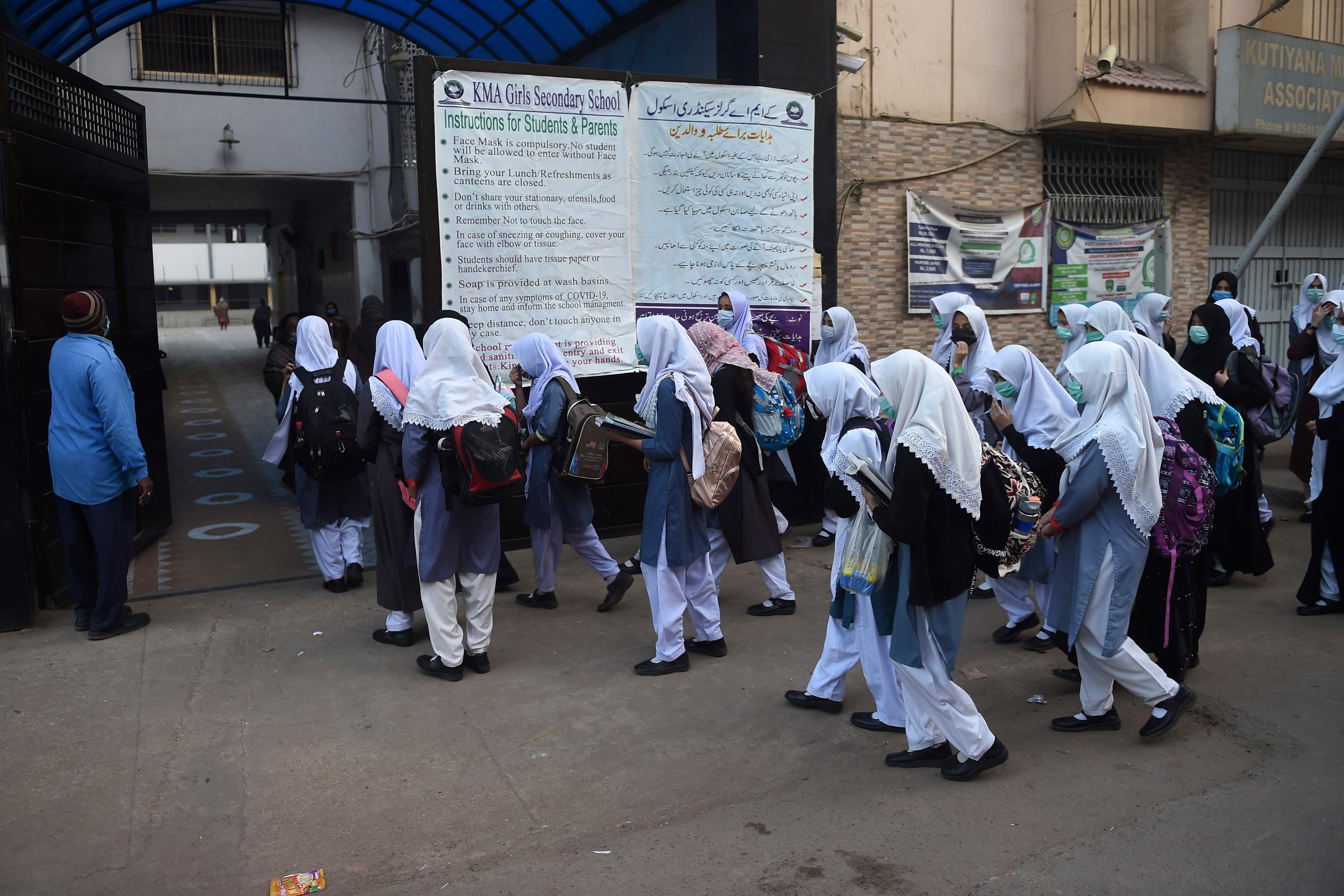 Students wearing facemasks arrive at the school in Karachi on January 18. — AFP