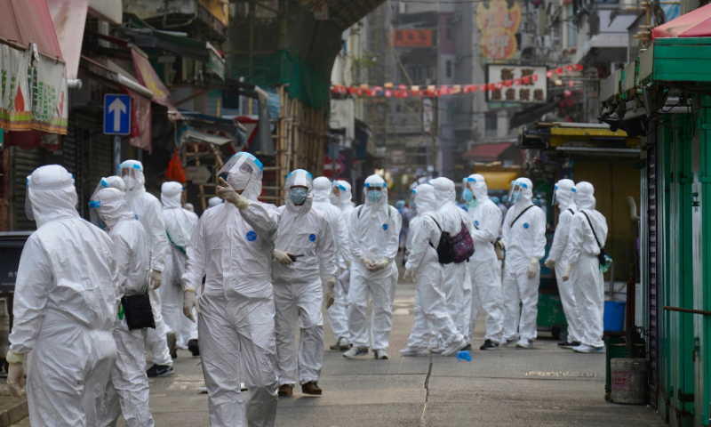 Government investigators wearing protective suits, gather in the Yau Ma Tei area, in Hong Kong on Saturday. — AP