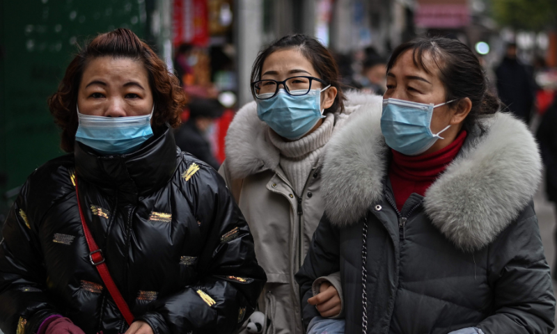 Pedestrians wearing face masks as a preventive measure against Covid-19 walk on a street in Wuhan, China's central Hubei province on January 22. — AFP