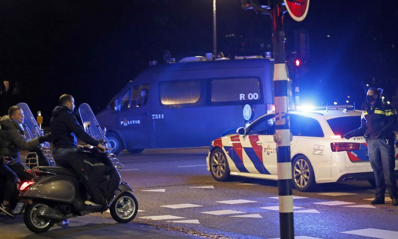 A police officer speaks to youths on scooters at a road block during a nation-wide curfew in Amsterdam, Netherlands on January 26. — AP