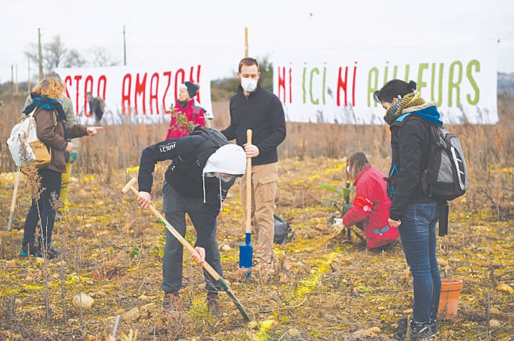 Activists of the Attac association plant trees in front of banners reading &ldquo;Stop Amazon&rdquo; and  &ldquo;Neither here nor elsewhere&rdquo;, during a demonstration on the site where Amazon plans to build a 38.800 square metres warehouse, in Fournes, southeastern France.&mdash;AFP